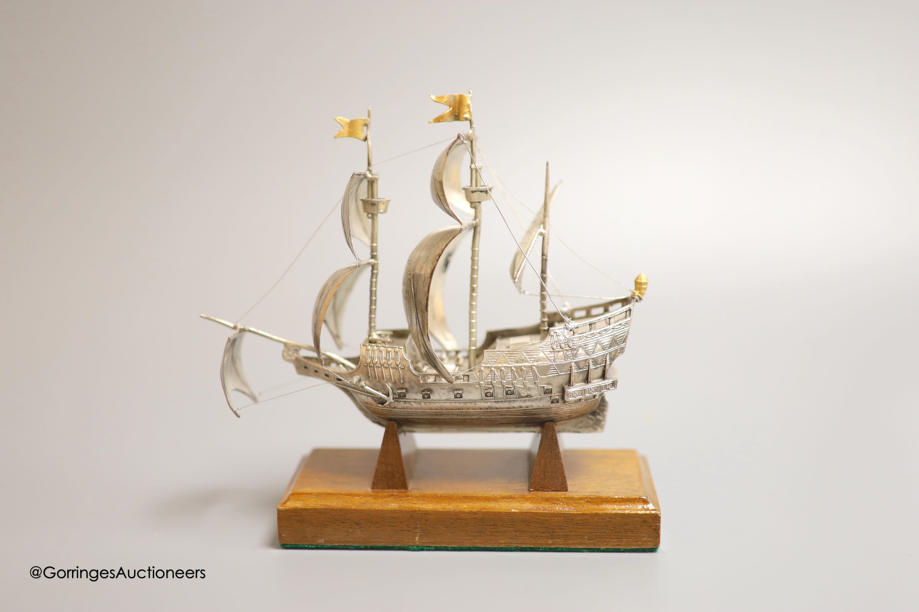 A modern Italian white metal (stamped 925) miniature model of the ship, 'The Golden Hind', (repairs), post 1968 mark, length 16cm, on a wooden stand
